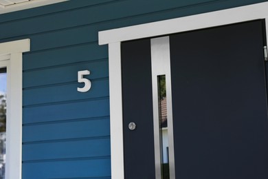 Photo of Number five on blue wooden house near door outdoors