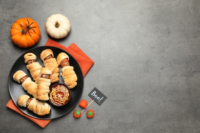 Photo of Spooky sausage mummies for Halloween party served on grey table, flat lay. Space for text