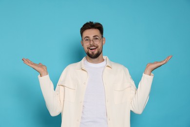 Surprised man in white jacket and eyeglasses on light blue background