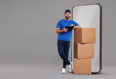 Image of Courier with stack of parcels and clipboard near huge smartphone on grey background. Delivery service. Space for text