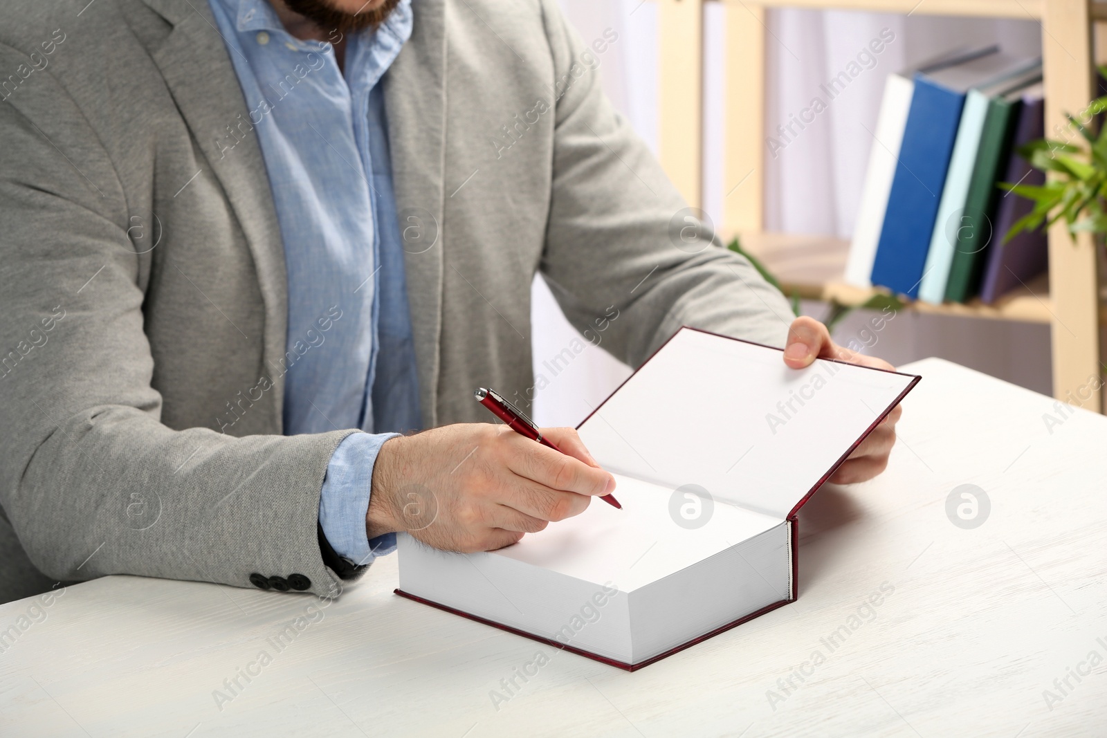 Photo of Writer signing autograph in book at table, closeup