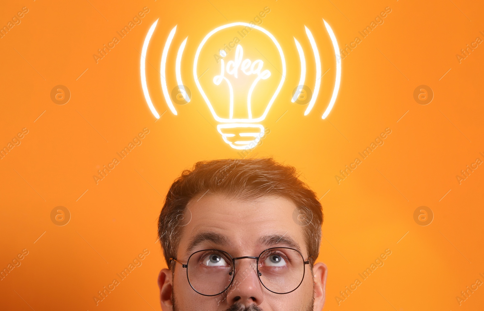 Image of Idea generation. Man looking at illustration of glowing light bulb over him on orange background