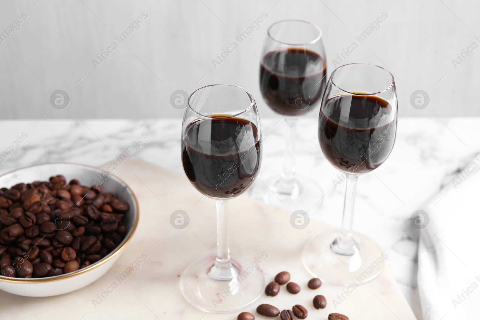 Photo of Glasses of coffee liqueur and beans on white table