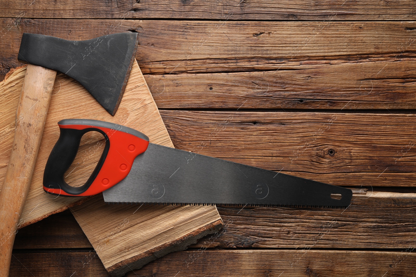 Photo of Saw with colorful handle and logs on wooden background, top view. Space for text