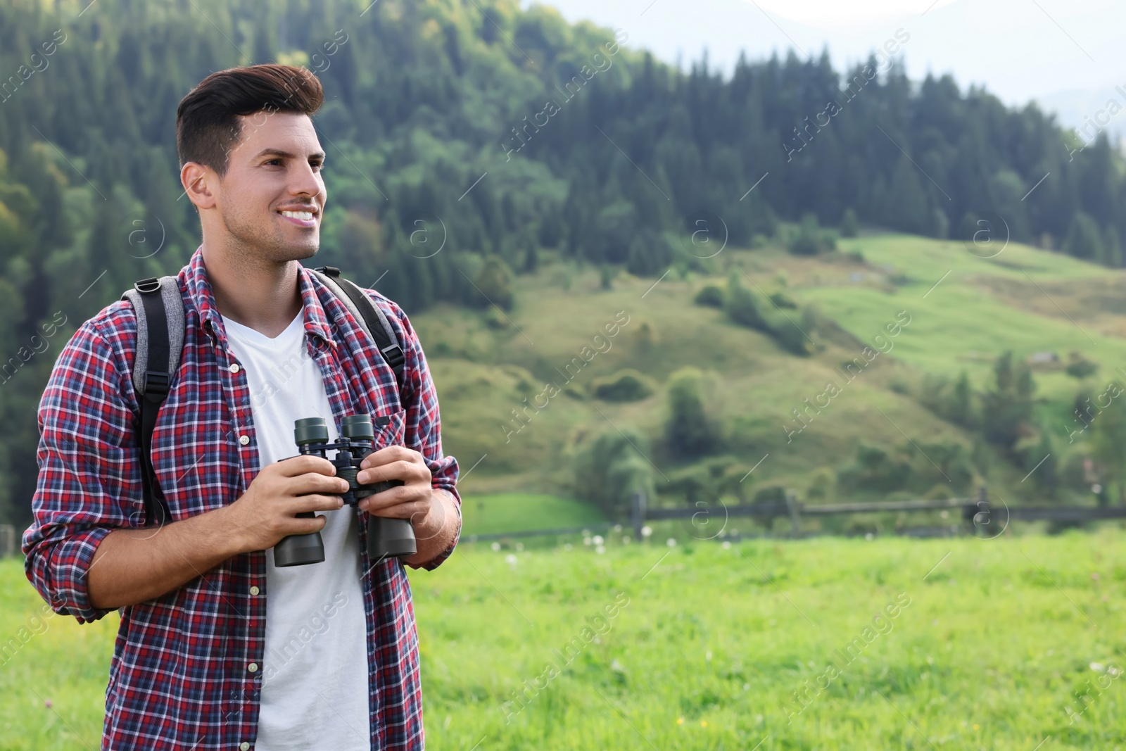 Photo of Man with backpack and binoculars in mountains