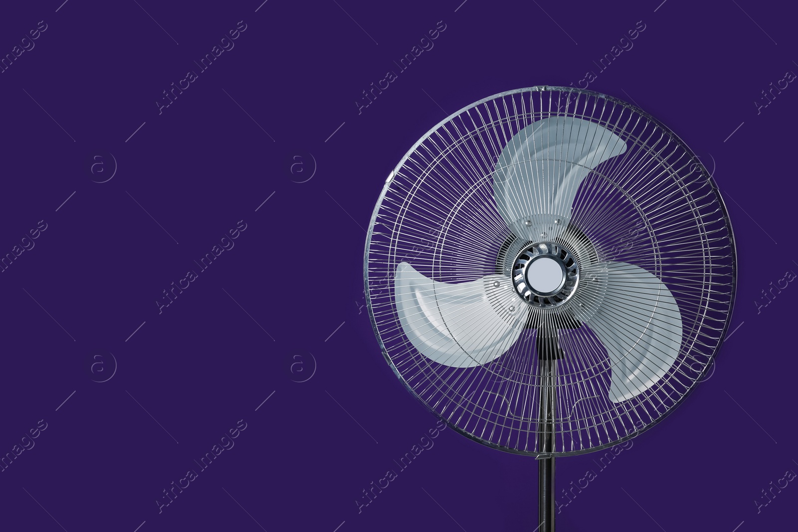 Photo of Modern electric fan on violet background. Space for text