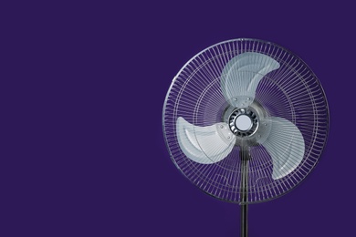 Photo of Modern electric fan on violet background. Space for text