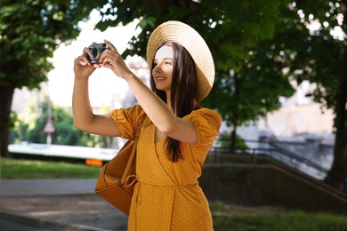 Travel blogger takIng picture with vintage camera outdoors