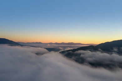 Image of Beautiful landscape with thick mist in mountains at sunset. Drone photography