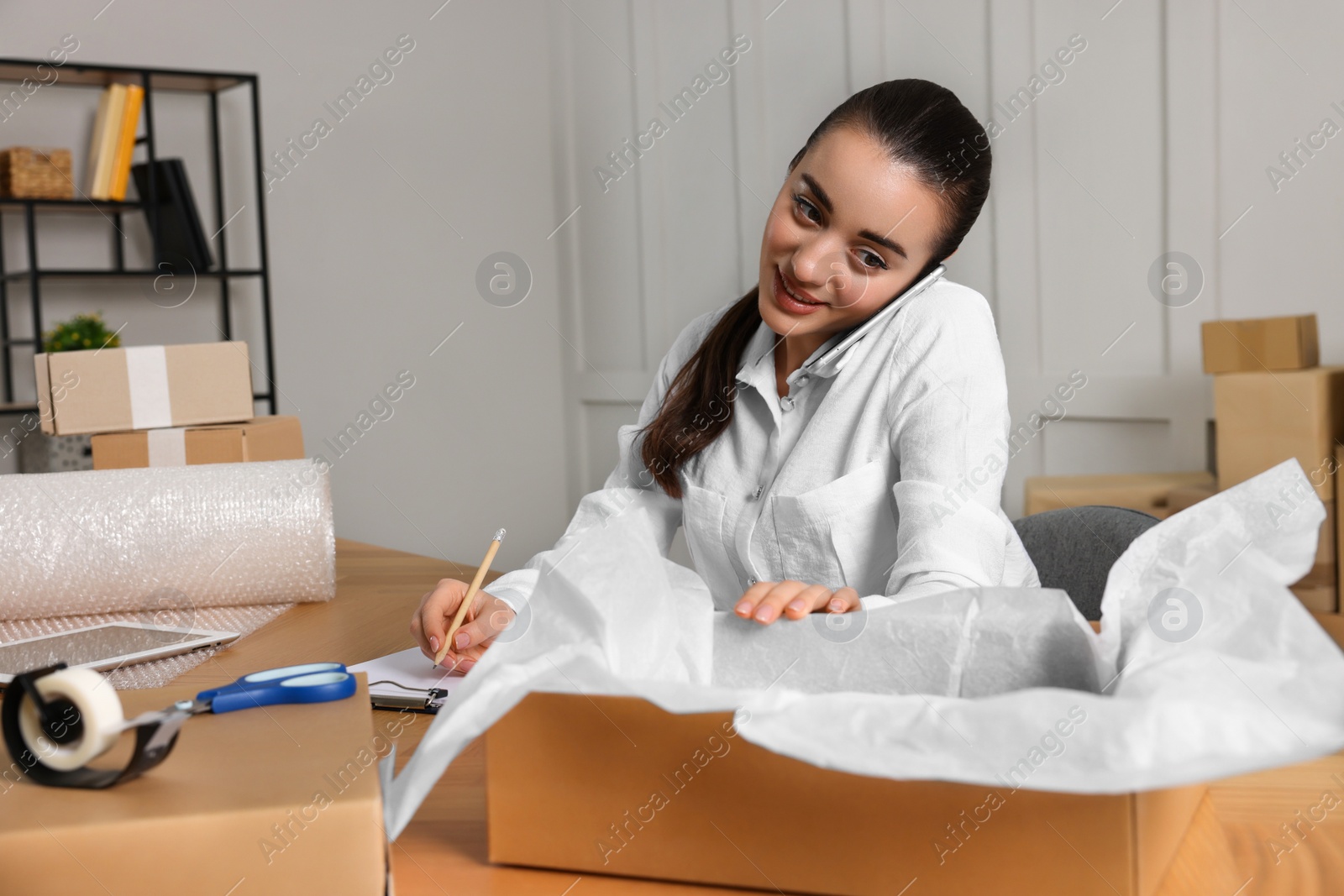 Photo of Seller talking on phone while working in office. Online store