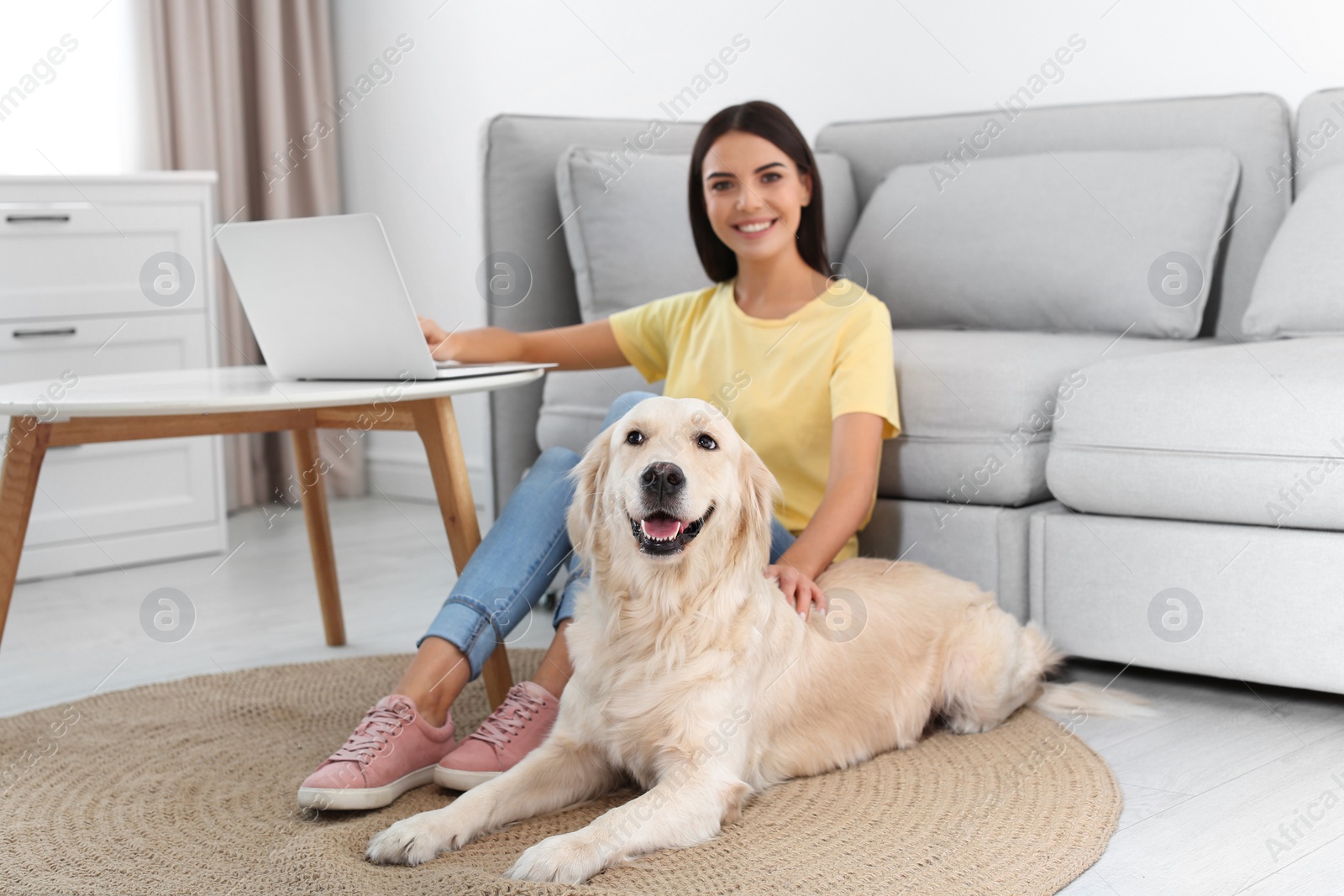 Photo of Young woman and her Golden Retriever dog in living room