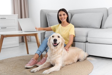 Photo of Young woman and her Golden Retriever dog in living room