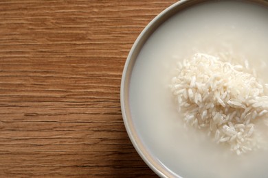 Photo of Rice soaked in water on wooden table, top view. Space for text