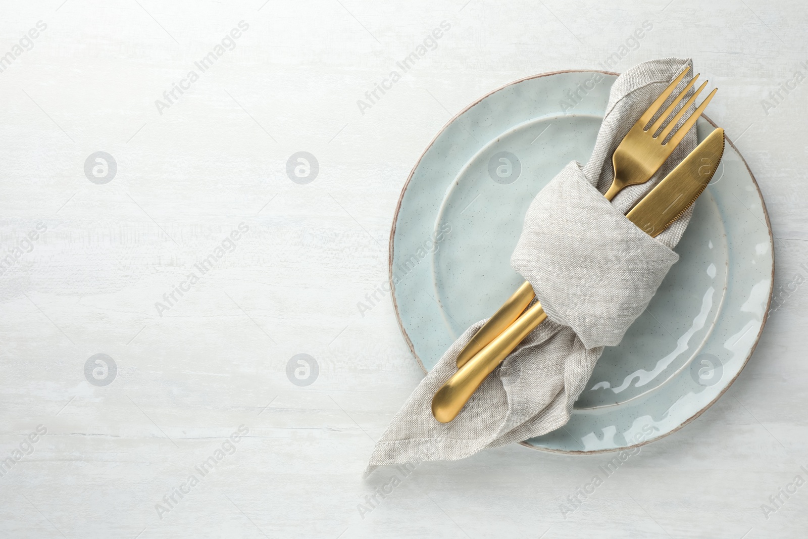 Photo of Stylish setting with cutlery, napkin and plates on white table, top view. Space for text