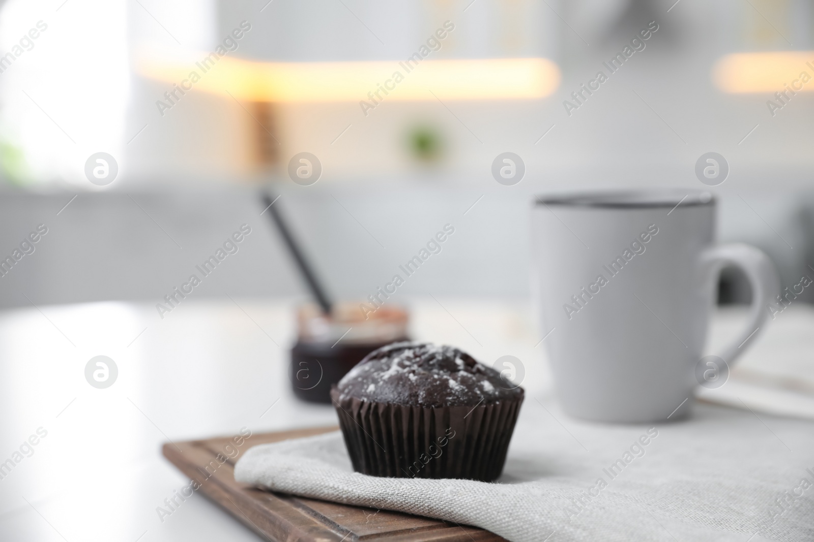 Photo of Delicious chocolate muffin on white table in kitchen. Space for text