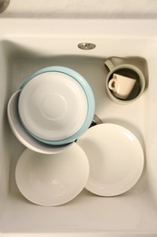 Photo of Clean tableware in white sink, top view