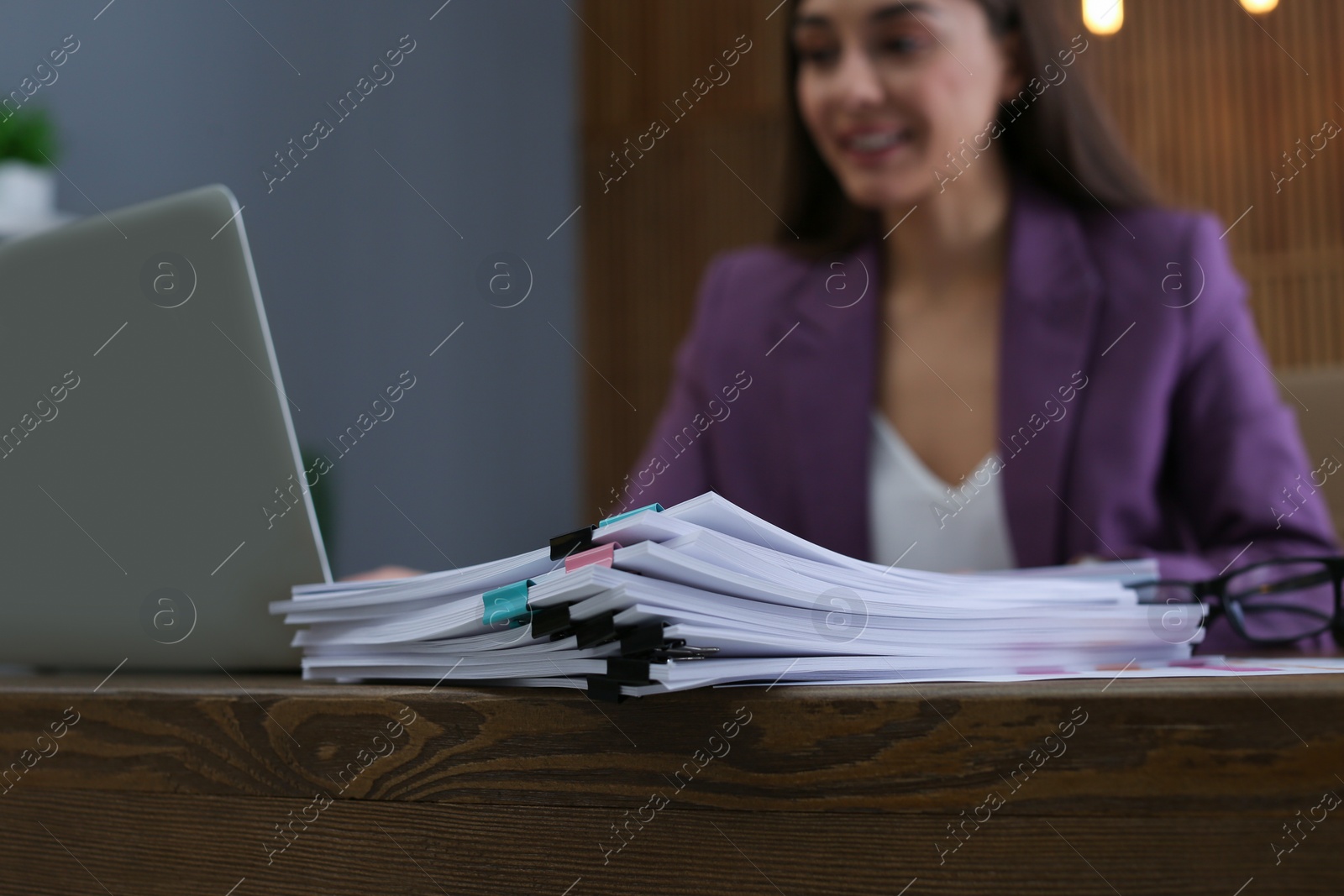 Photo of Stack of documents and blurred businesswoman on background