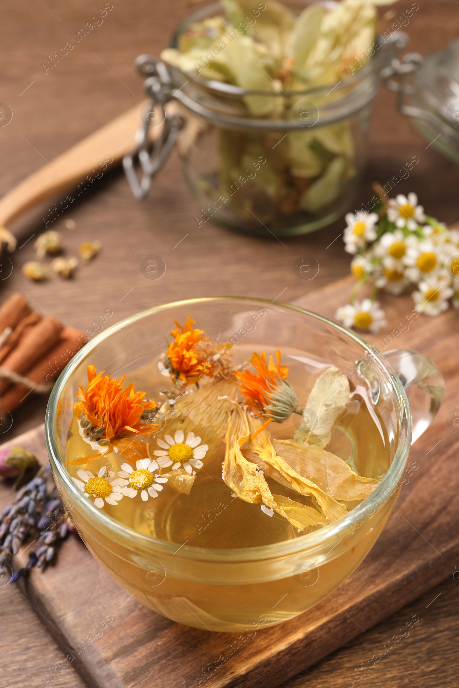 Photo of Freshly brewed tea and dried herbs on wooden table