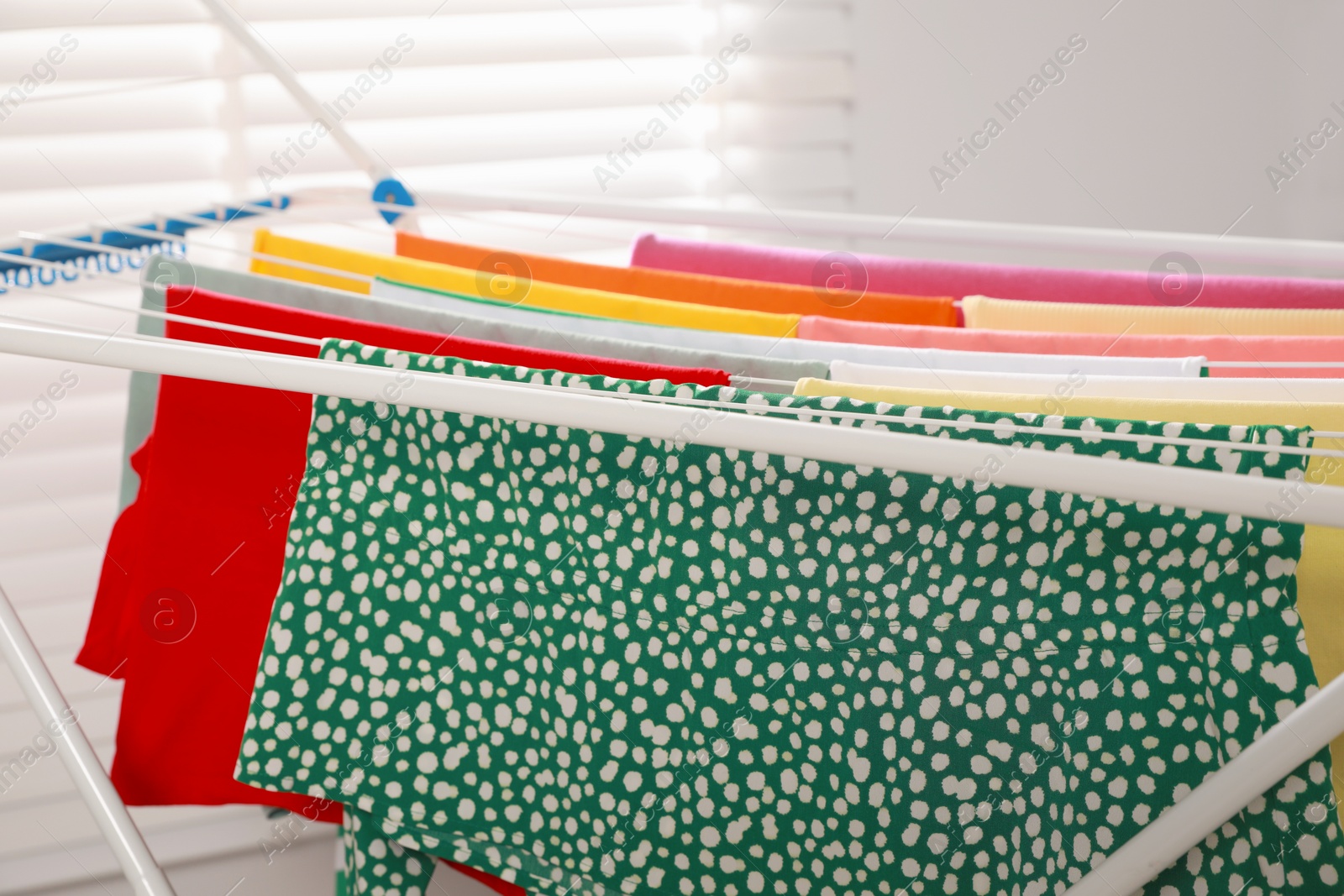 Photo of Different apparel drying on clothes airer indoors