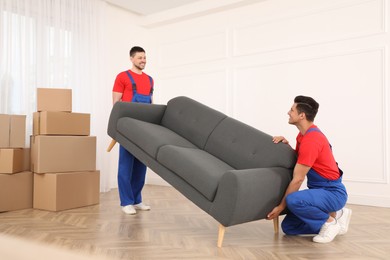 Photo of Professional movers carrying sofa in new house