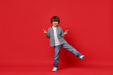 Happy little boy dancing on red background. Space for text