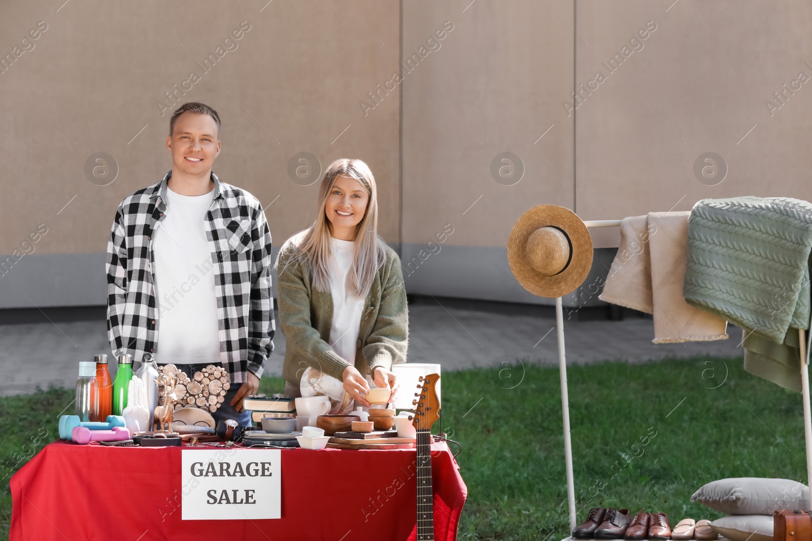 Photo of Happy family selling different items on garage sale in yard