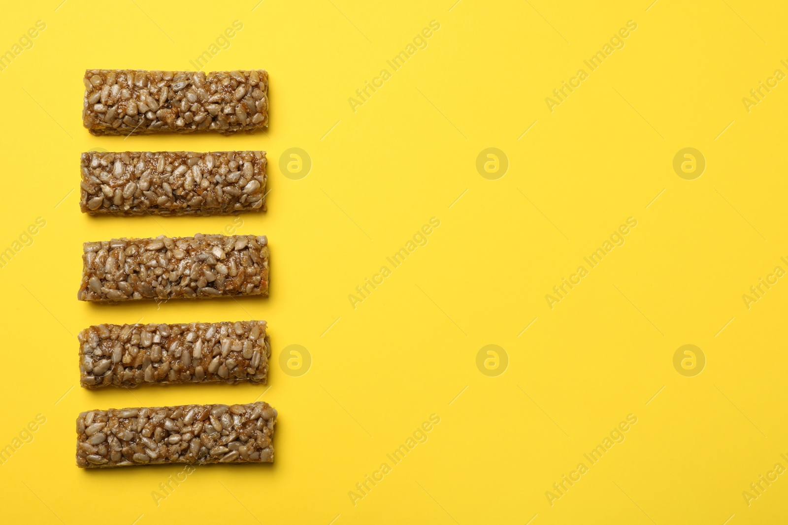 Photo of Delicious kozinaki bars on yellow background, flat lay. Space for text