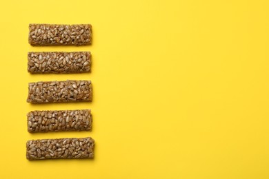 Photo of Delicious kozinaki bars on yellow background, flat lay. Space for text