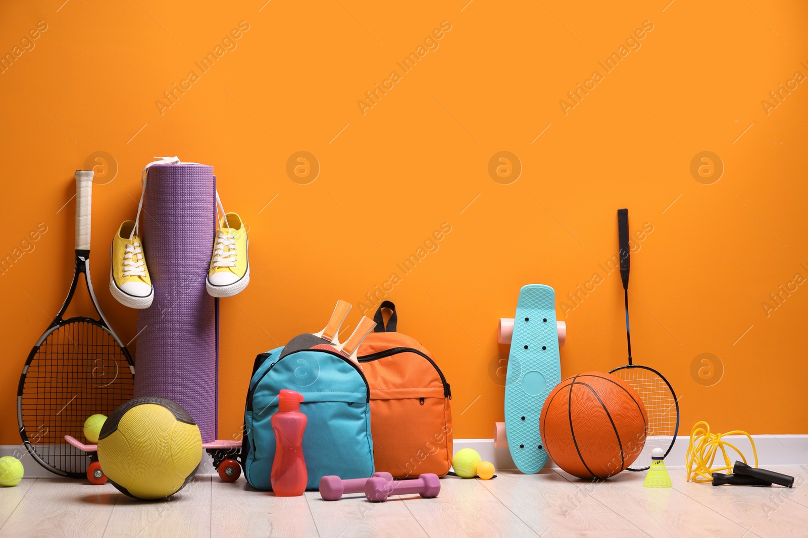 Photo of Many different sports equipment near orange wall indoors
