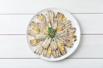 Photo of Tasty pickled anchovies with spices on white wooden table, top view