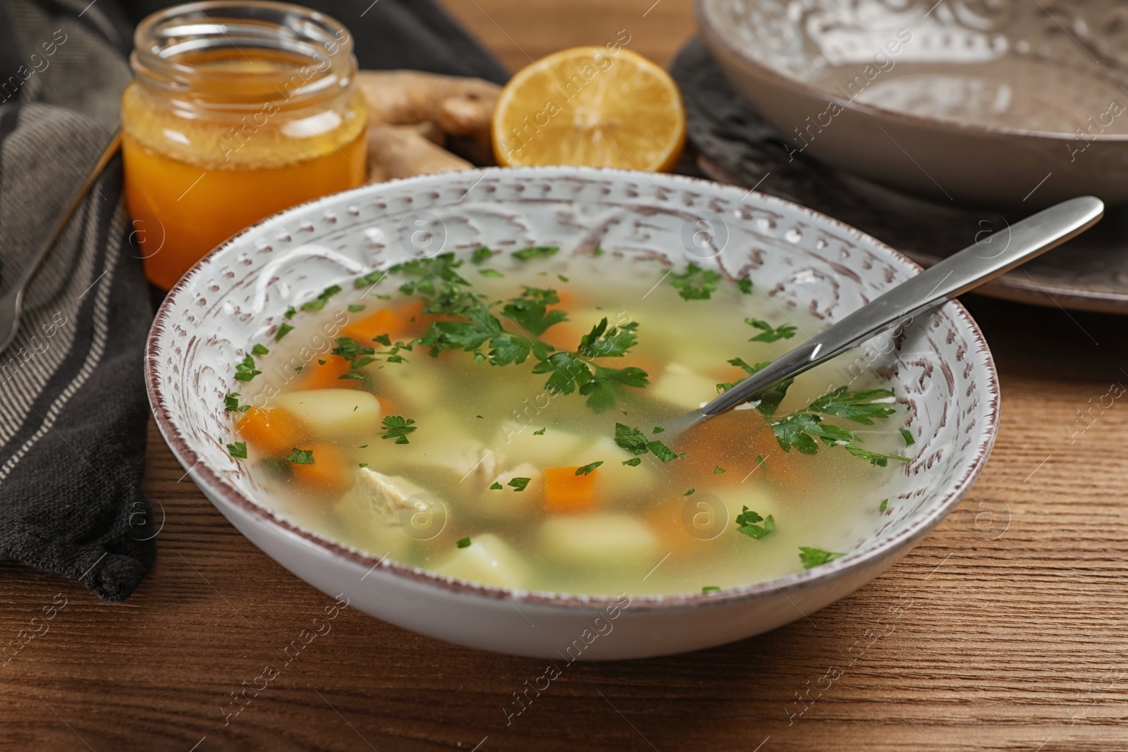 Photo of Bowl of fresh homemade soup to cure flu on wooden table