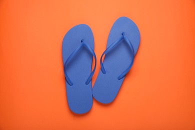 Photo of Stylish blue flip flops on orange background, top view