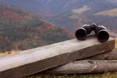 Photo of Binoculars on wooden fence in mountains, space for text