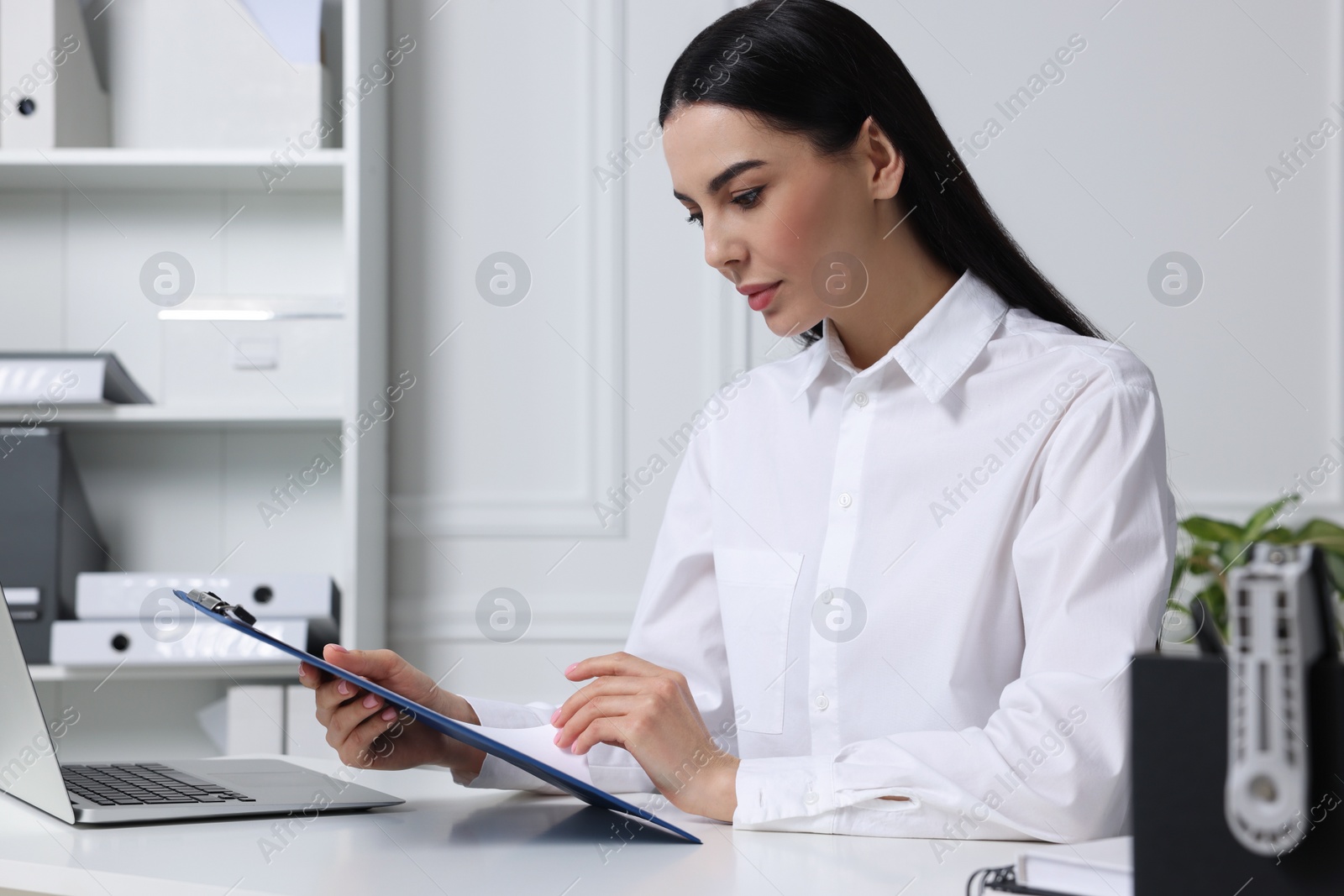 Photo of Human resources manager reading applicant's resume at white table in office