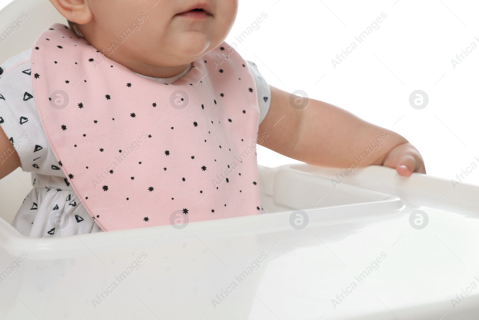 Photo of Cute little baby wearing bib in highchair on white background, closeup