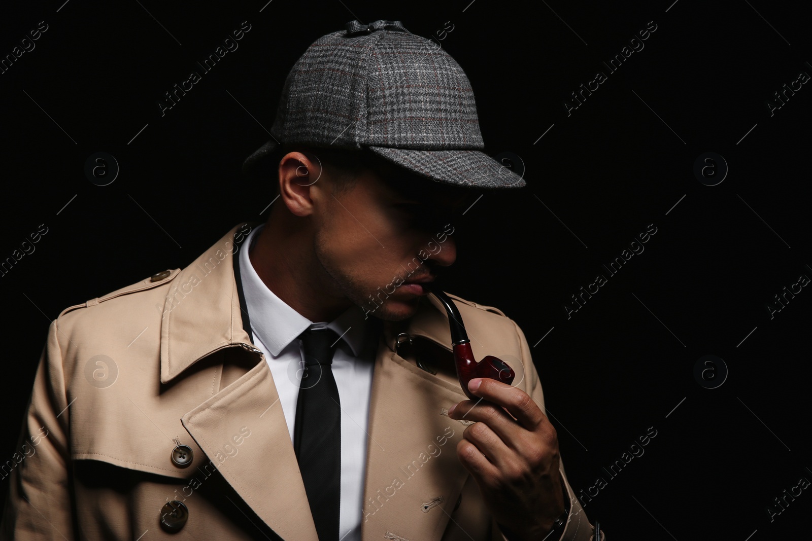 Photo of Old fashioned detective with smoking pipe on dark background