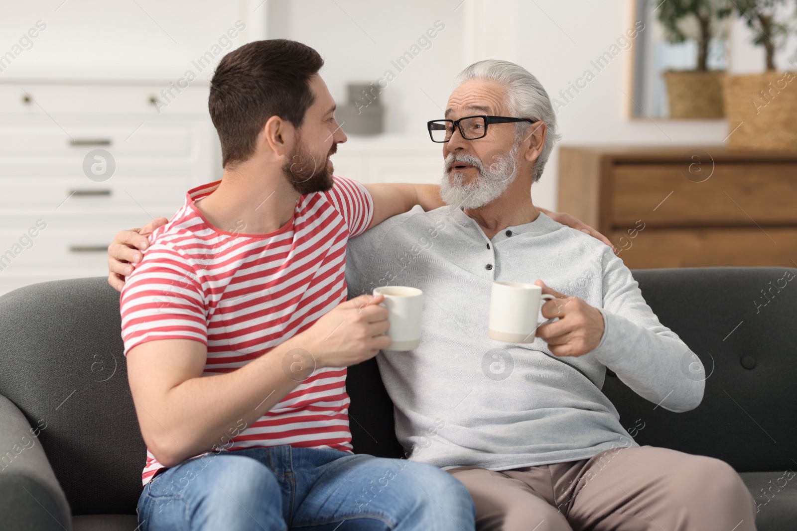 Photo of Happy son and his dad with cups at home