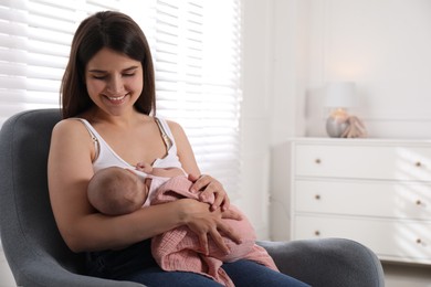 Young woman breastfeeding her little baby at home, space for text