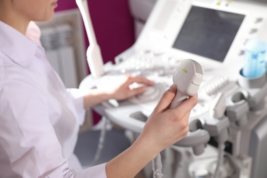 Photo of Sonographer holding ultrasound machine probe in clinic, closeup