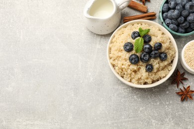 Photo of Flat lay composition with bowl of tasty quinoa porridge and blueberries on light grey table. Space for text