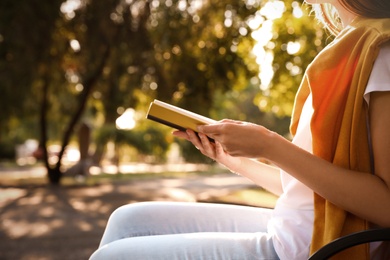 Photo of Young woman reading book outdoors, closeup view