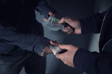 Addicted man buying drugs from dealer on blurred background, closeup