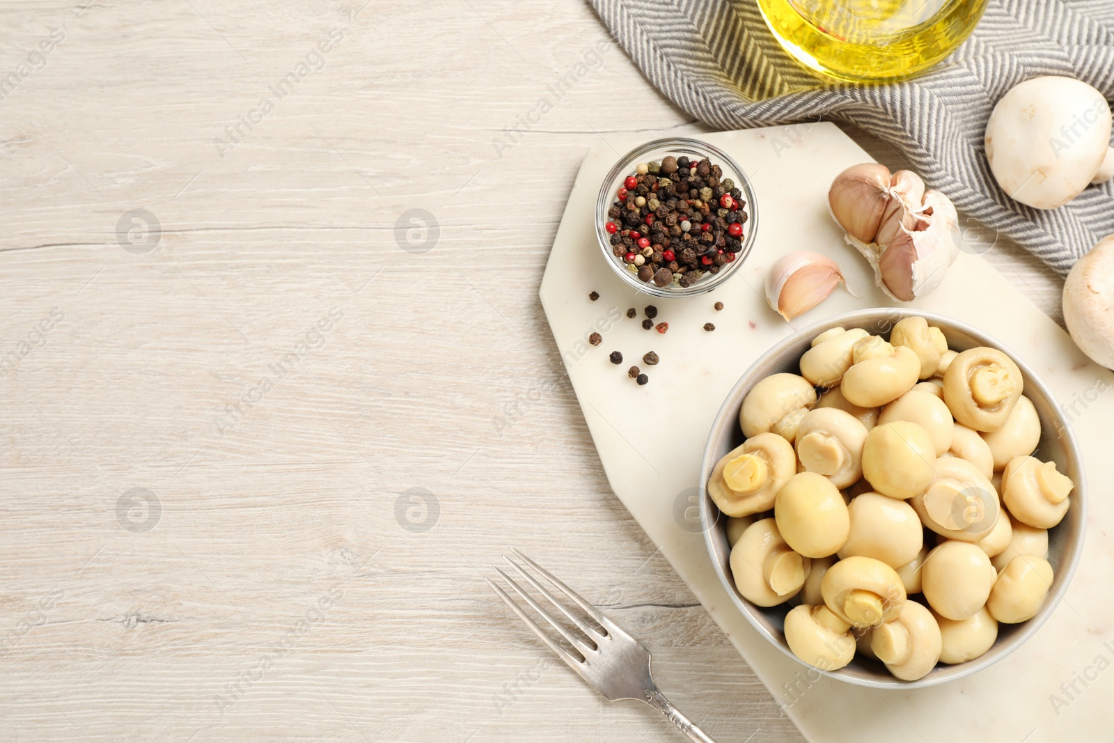 Photo of Tasty marinated mushrooms on white wooden table, flat lay. Space for text