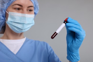 Photo of Laboratory testing. Doctor with blood sample in tube on light grey background