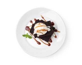 Photo of Tasty brownies with ice cream, mint and caramel sauce isolated on white, top view
