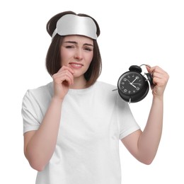 Photo of Unhappy young woman with sleep mask and alarm clock on white background. Insomnia problem