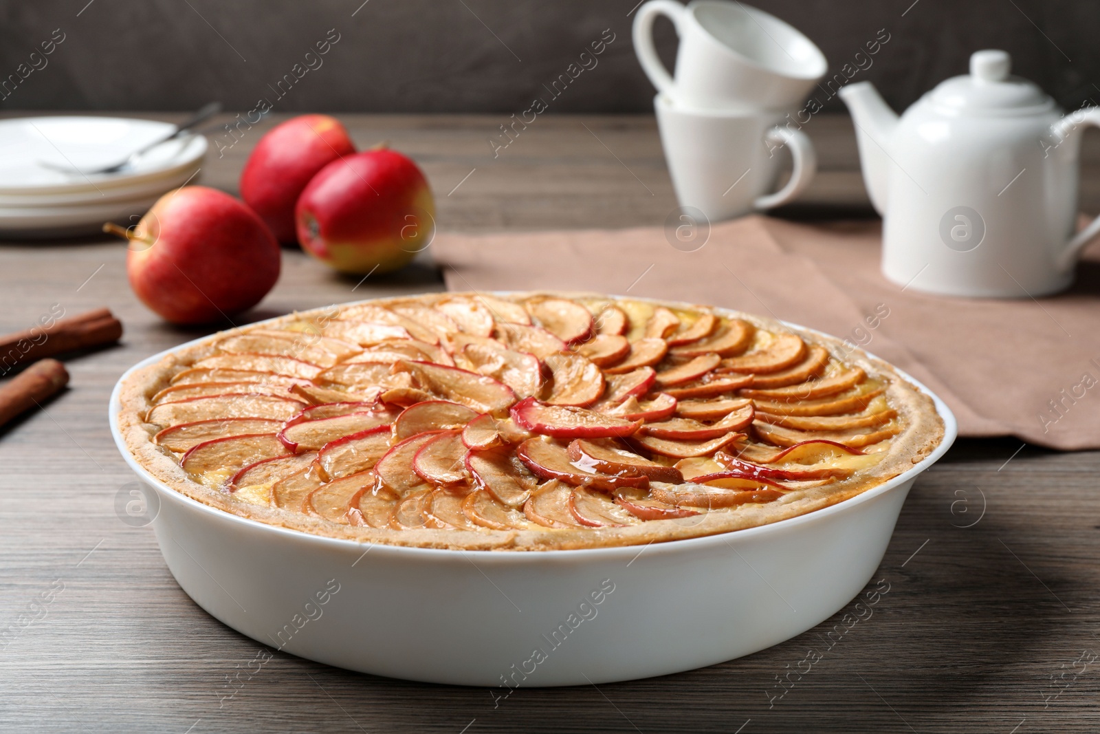 Photo of Tasty apple pie in baking dish on wooden table