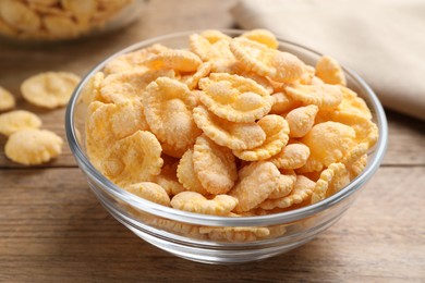 Photo of Bowl with tasty corn flakes on wooden table, closeup