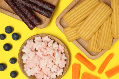 Photo of Different finger foods for baby on yellow background, flat lay
