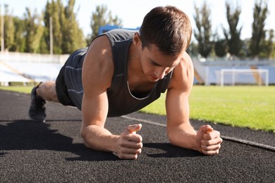 Photo of Sporty man doing plank exercise at stadium